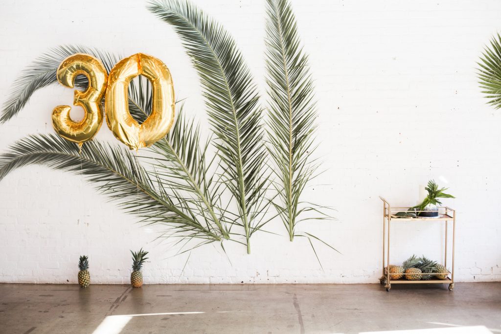 tropical theme 30th birthday chic party ideas backdrop palm leaves branches 